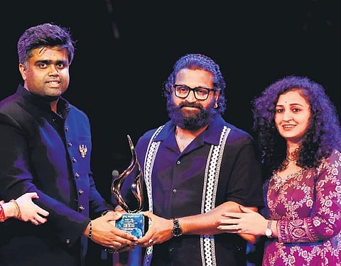 Rishab Shetty along with wife, Pragathi Shetty receiving the trophy