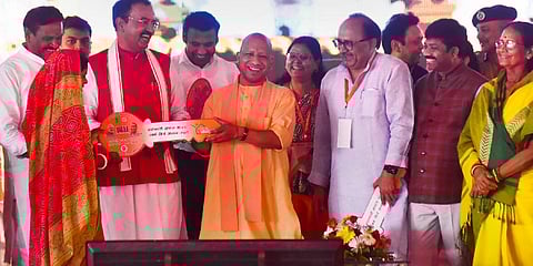 Uttar Pradesh CM Yogi Adityanath with Deputy CM Keshav Prasad Maurya hands over a symbolic key to a beneficiary during 'Grih Pravesh' for 76 flats constructed under Pradhan Mantri Aawas Yojna at Lukar