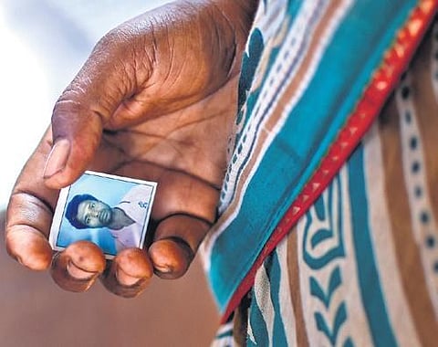 A woman holds a photo of her son who died in the train crash, outside AIIMS in Bhubaneswar, on Monday. (Photo | Debadatta Mallick)
