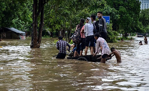 People wade through a waterlogged street after heavy rains (Photo | PTI)