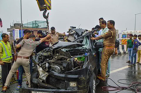 Police personnel and others near the wreckage of a car after a head-on collision with a bus on Ghaziabad-Meerut Expressway, in Ghaziabad. 