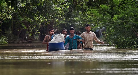 People from low-lying areas around the Yamuna river wade through floodwaters of the swollen river while relocating to a safer place, in New Delhi.(PTI Photo)