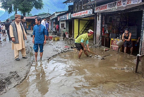 Residents remove rainwater from a shop after heavy monsoon rains, in Kullu, Tuesday, July 11, 2023. (Photo | PTI)