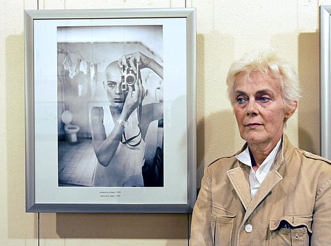 French press photographer Marie-Laure de Decker poses next to a self-portrait of her exhibition. (Photo|AFP)