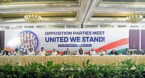 Leaders from India's top Opposition parties sit in front of a huge banner with the 'United We Stand' slogan during their dinner meeting in Bengaluru on Monday, July 17, 2023. (Photo | ANI)