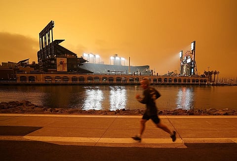 FILE - A jogger runs along McCovey Cove outside Oracle Park in San Francisco, under darkened skies from wildfire smoke on Sept. 9, 2020. (Photo | AP)