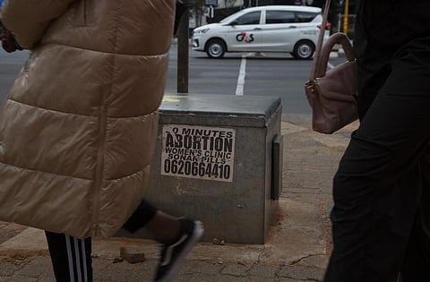 Women pass a sticker advertising abortion pills on a sidewalk in Johannesburg, Wednesday June 28, 2023. (Photo | AP)