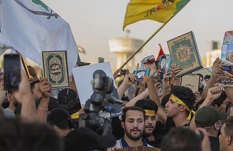 Iraqis raise copies of the Quran, Muslims' holy book, during a protest in Tahrir Square. (Photo | AP)