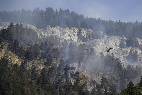 A helicopter pours water on the still burning forest above the communes of Bitsch and Ried-Moerel, in Bietsch, Switzerland
