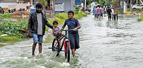 Residents help a girl cross the flooded streets of Gajularamaram on a bicycle; Vinay Madapu