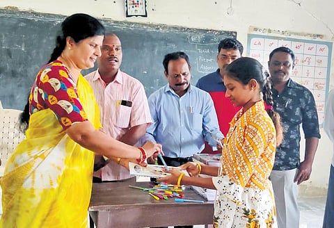 A student of a government school receives pens and notebooks from 'My Vemulawada Charitable Trust'.