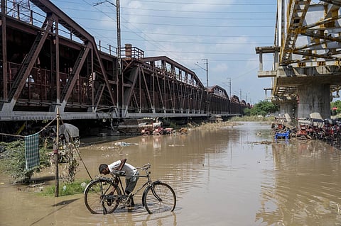A cyclist at the bank of swollen Yamuna river near the Old Yamuna Bridge (Loha Pul), in New Delhi, Monday, July 24, 2023. (PTI)