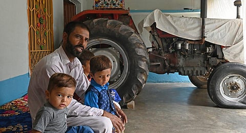 In this picture taken on July 18, 2023, Pakistani worker Muhammad Naeem Butt sits with his children at his home in Khuiratta. (Photo | AFP)