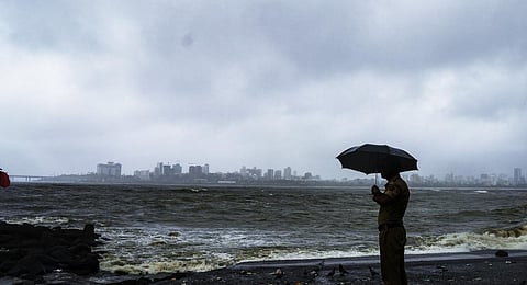 A police personnel stand guard at the coastline amid monsoon rains as high tidal waves crash at the shore, in Mumbai. (Photo | PTI)