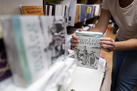 An employee of a bookstore wraps a book featuring LGBTQ+ content in closed packaging to comply with a contentious law on homosexuality in media. (Photo | AP)
