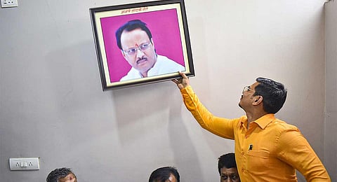 Nationalist Congress Party (NCP) workers remove a photo of Maharashtra Deputy Chief Minister Ajit Pawar from the party office as part of a protest, in Solapur, Monday, July 3, 2023. (PTI)