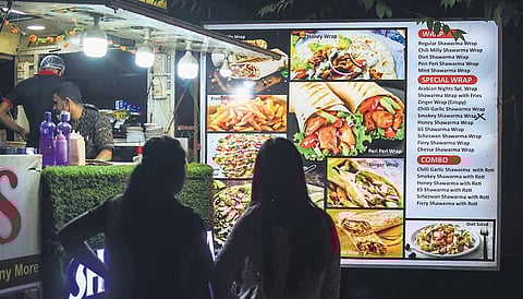 Customers look at the menu chart of a roadside food stall in Bhubaneswar