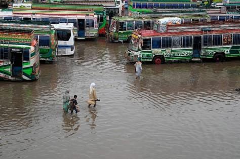 Passengers wade through a flooded bus terminal caused by heavy monsoon rainfall in Lahore, Pakistan, Wednesday, July 5, 2023. (AP)