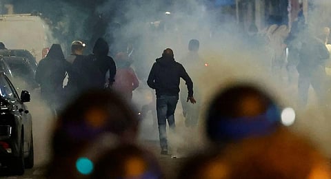 Demonstrators run as French police officers use tear gas in Paris. (Photo | AFP)