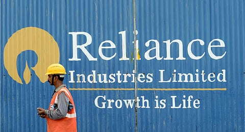 FILE - A worker walks past the signage of Reliance Industries Limited (RIL) in Mumbai. (Photo | AFP)