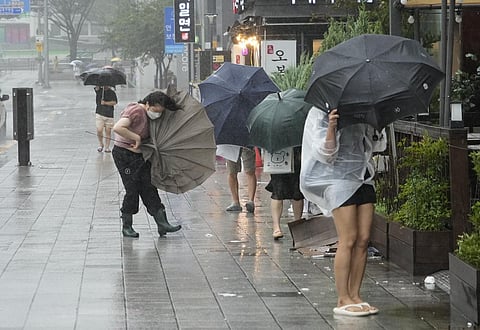 People struggle to hold onto their umbrellas in the rain and wind as the tropical storm named Khanun approaches to the Korean Peninsular, in Busan