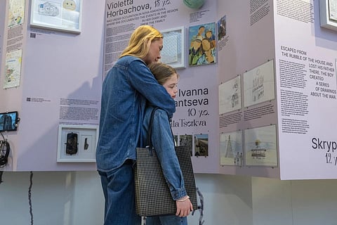 Eight-year-old Michelle Potapova is hugged by her mother Natali Hrushevska as they look at the War Diaries exhibition. (Photo | AP)