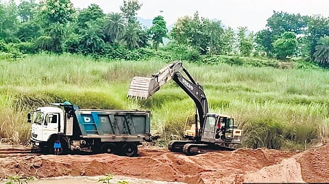A JCB machine engaged in lifting sand from the bank of Bahuda river in Chikiti