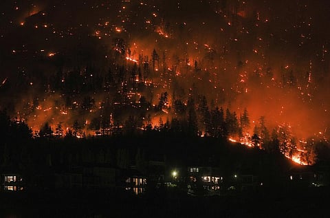 The McDougall Creek wildfire burns on the mountainside above houses in West Kelowna, B.C., on Friday, Aug. 18, 2023. (Photo | AP)