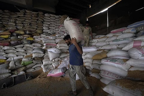A Pakistani worker carries sacks of wheat in a warehouse in Karachi, Pakistan, on Wednesday, July 26, 2023. (Photo | AP)