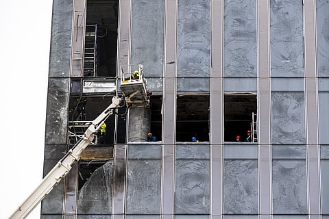 Workers clean a part of a damaged skyscraper in the 'Moscow City' business district after a reported drone attack. (Photo | AP)