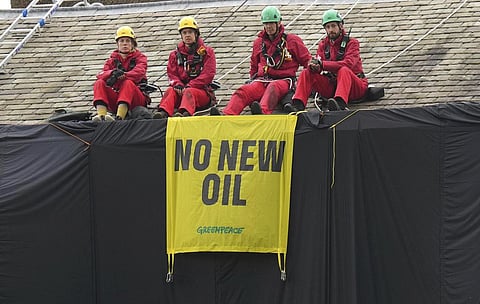 Greenpeace activists sit on the roof of Britain's Prime Minister Rishi Sunak's house in Richmond, North Yorkshire, England, after covering it in black fabric. (Photo | AP)