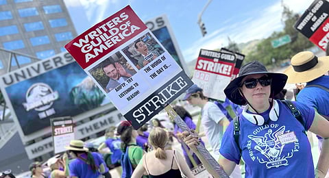 Writer Julie Benson holds a picket sign with an image of the late actor and comic Paul Reubens, dressed as his character Pee-wee Herman, outside Universal Studios on Tuesday. (Photo | AP)