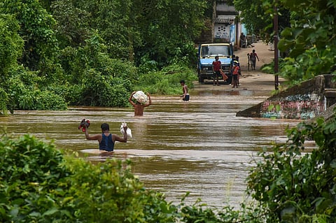 Residents of Kainmundi Village wades through flooded road at Banki in Cuttack district on Thursday. (Photo | EPS/ Debadatta Mallick)