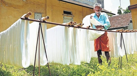 Ratnan K P (Kuttan), who has been working in the handloom sector for nearly five decades,  hanging bleached yarn for drying in the sun. (Photo | T P Sooraj)