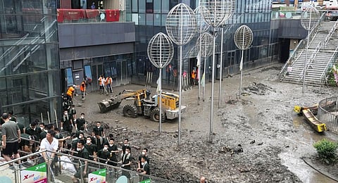 Soldiers and workers clear mud clogged on a square of a commercial office building in the aftermath of flood waters from an overflowing river in the Mentougou district. (Photo | AP)