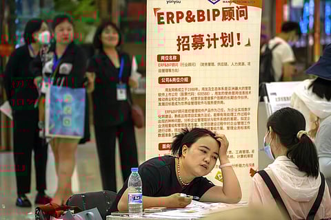 FILE - A recruiter talks with an applicant at a booth at a job fair at a shopping center in Beijing, on June 9, 2023. (Photo | AP)