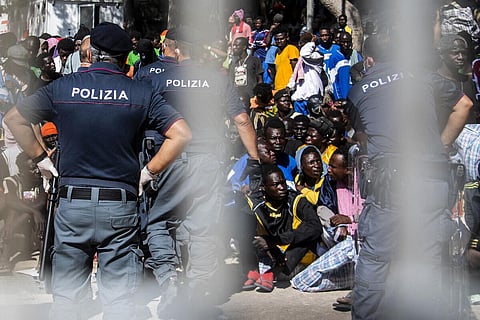 Migrants gather outside the operational center called 'Hotspot' on the Italian island of Lampedusa on September 14, 2023. (Photo | AFP)