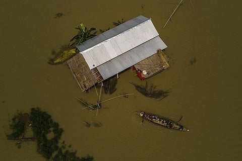 Residents leave their submerged house on a boat in Sandahkhaiti, a floating island village in the Brahmaputra River in Morigaon district, Assam, Aug. 30, 2023. (Photo | AP)