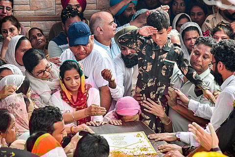 Son of Colonel Manpreet Singh salutes as family members and relatives mourn near his mortal remains before his last rites, at his native place in Mohali, Friday, Sept. 15, 2023. (Photo | PTI)