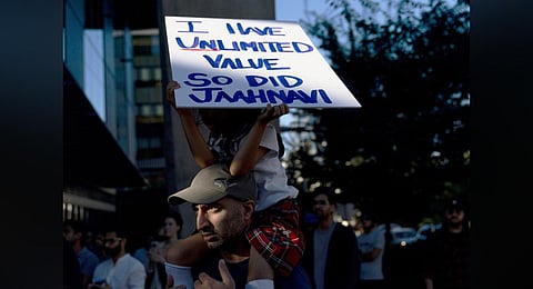 A girl sits atop her father's shoulders while holding a sign for Jaahnavi Kandula, during a protest in Seattle, after the footage of a cop joking about her death came to light. (Photo | AP)