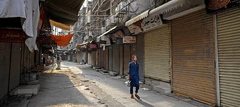 A boy walks past closed shops along a street in Peshawar on September 2, 2023, during a nationwide strike by traders against the surge in electricity and fuel prices. (Photo | AFP)