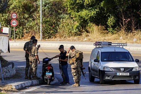 Lebanese soldiers check a driver motorcycle document as investigators collect forensic evidence outside U.S. Embassy in Aukar. (Photo | AP)