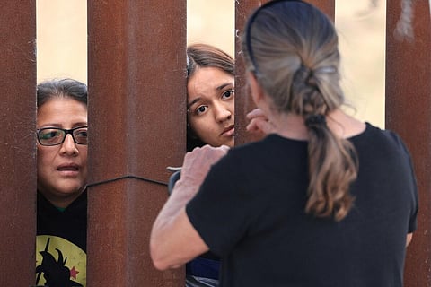 An aid volunteer talks with migrant women between the primary and secondary fences of the border between Mexico and the United States in San Diego, California. (Photo | AFP)