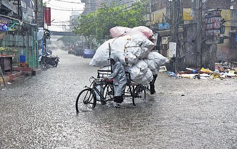 Amid heavy showers, a cart puller is seen crossing a waterlogged street in the Old City area of Hyderabad on Wednesday. (Photo | Vinay Madapu)
