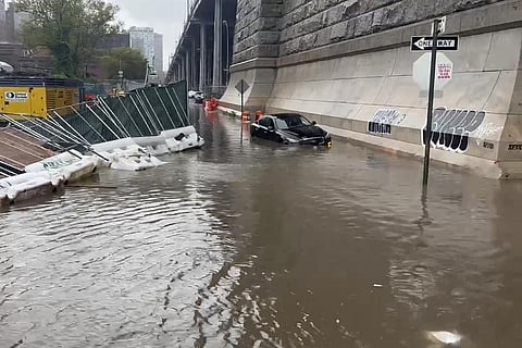 A car sits stranded in flood waters at the base of the Williamsburg Bridge. (Photo | AP)