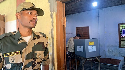 A security personnel stands guard as a voter casts his vote during by-elections to Boxanagar assembly seat, in Tripura's Sepahijala district, Tuesday, Sept. 5, 2023. (Photo | PTI)