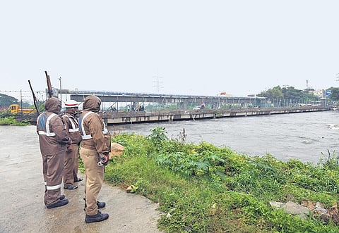 Police personnel observe the flow of Musi river near the Moosarambagh causeway in Hyderabad after heavy rains on Tuesday. (Photo | Vinay Madapu)