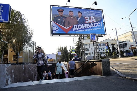 People walks along a street decorated with a United Russia party poster prior to local elections in Donetsk, the capital of Russian-controlled Donetsk region. (Photo | AP)