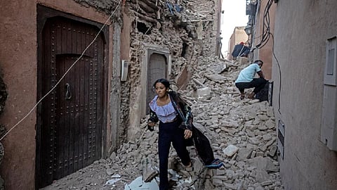 A woman evacuates with her belongings through the rubble in the earthquake-damaged old city of Marrakesh on September 9, 2023. (Photo | AFP)