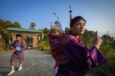 A Bhutanese woman carrying her child on her back shows the voting mark on her index finger after casting her vote in the national elections in Deothang, Bhutan. (Photo | AP)